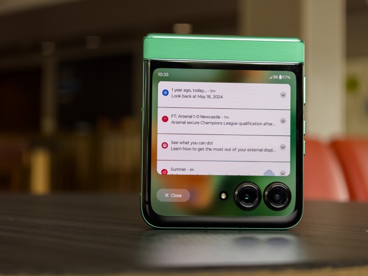alt: The Motorola Razr 2025 partially open, displaying recent notifications on the cover display.