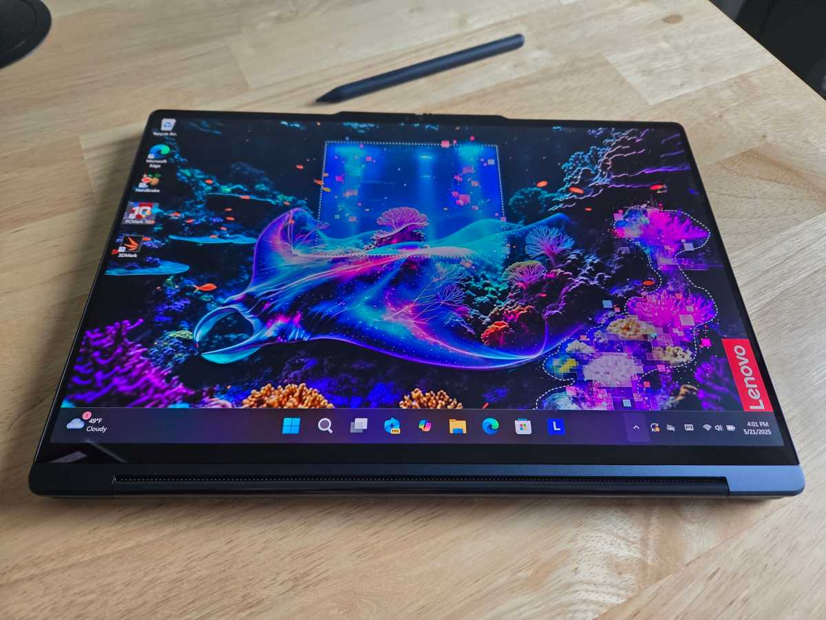 The Lenovo Yoga 9i 2-in-1 laid flat in tablet mode with the Yoga Pen resting on its screen, demonstrating touch and pen input.