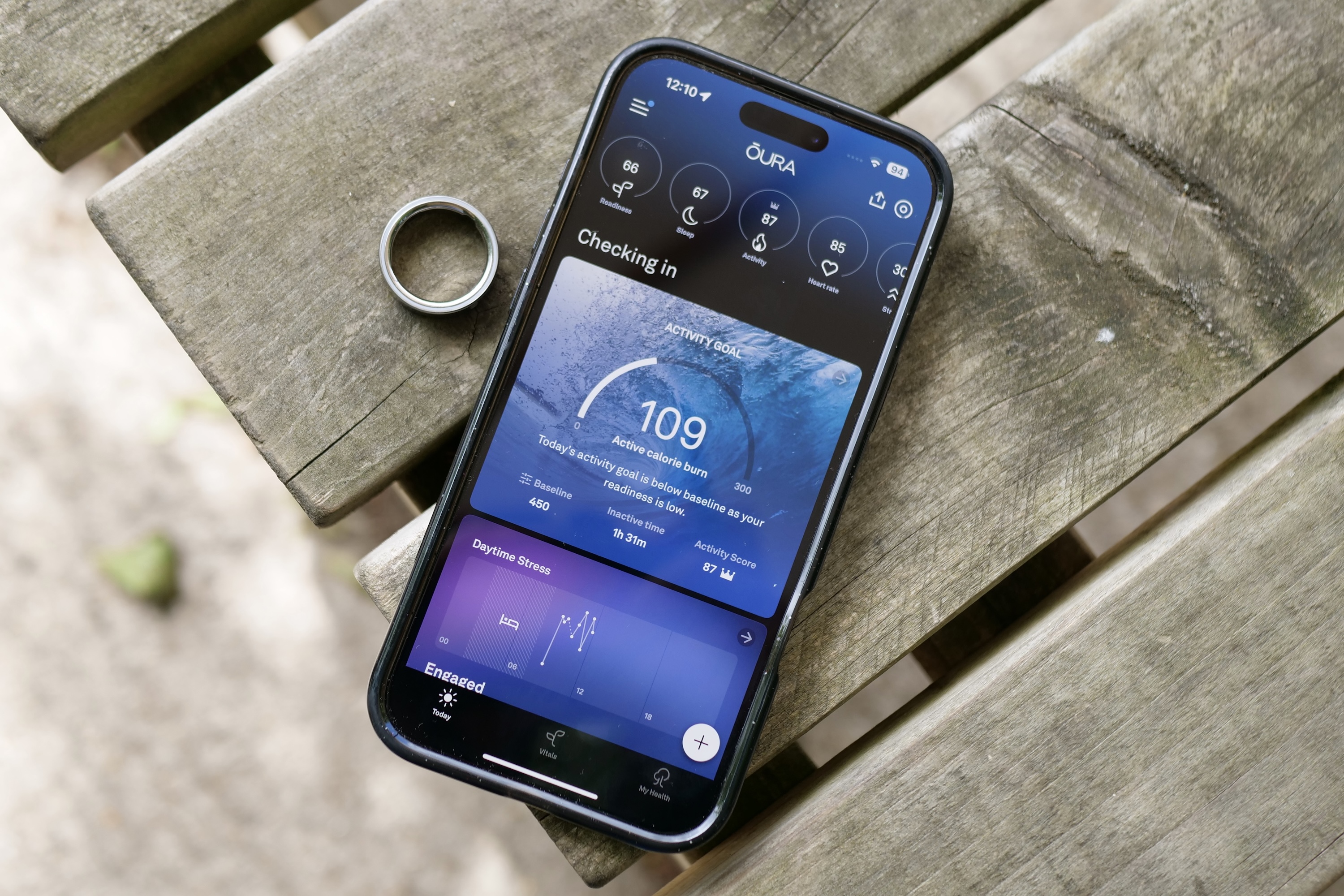 The Oura Ring 4 placed next to a smartphone showcasing the Oura app's user-friendly dashboard.