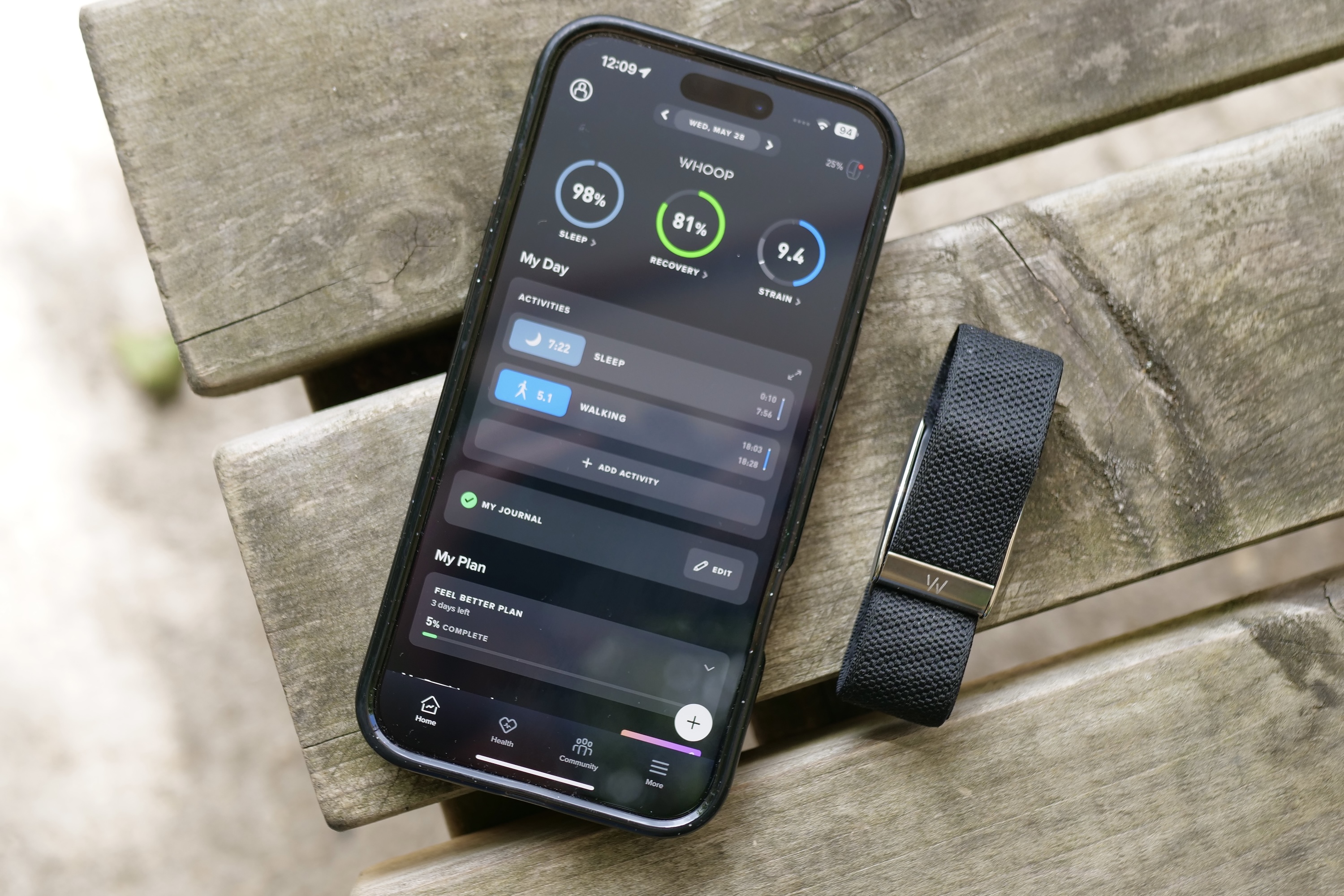 The Whoop 5.0 fitness tracker alongside a smartphone displaying the Whoop app interface.
