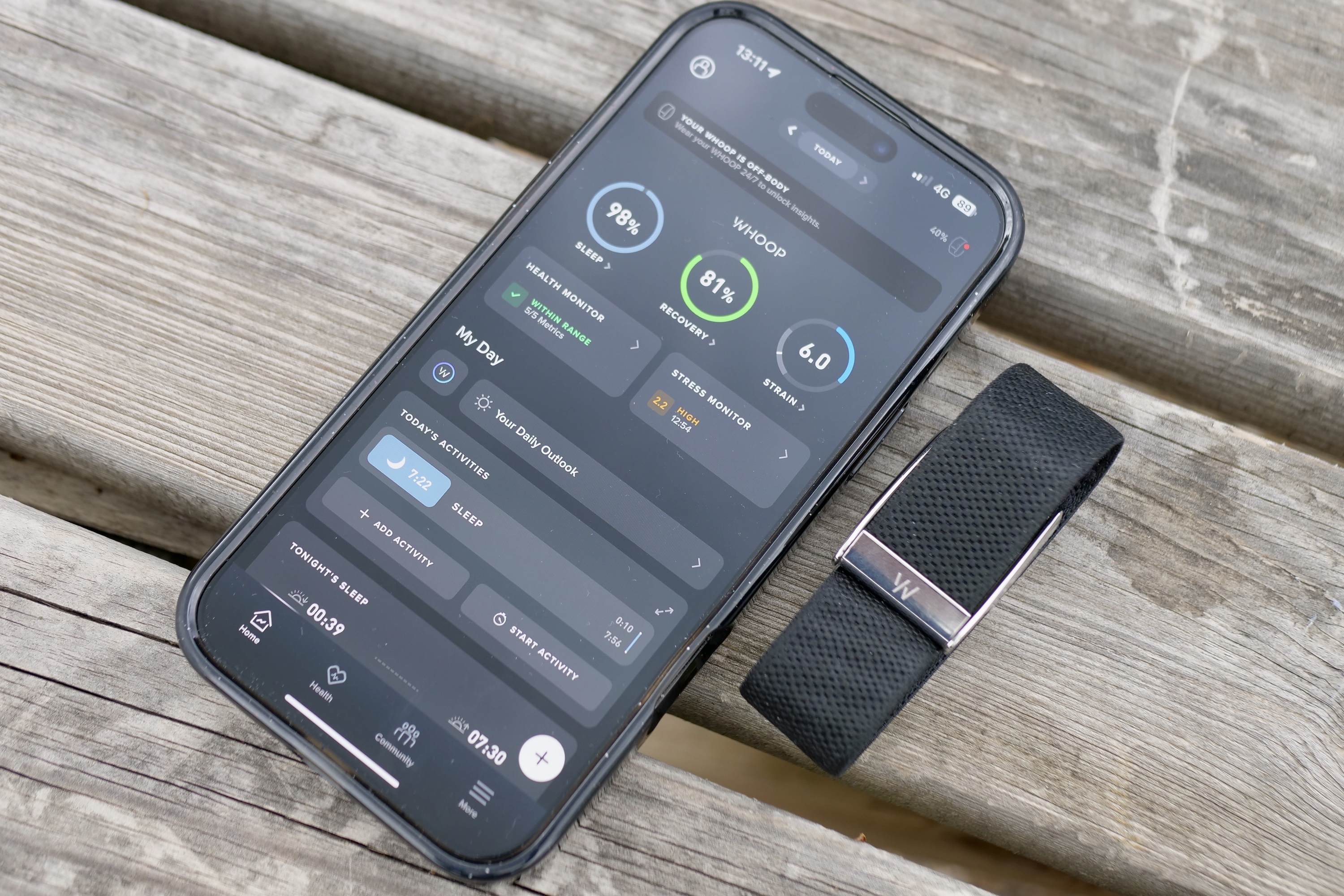 Whoop 5.0 app interface displaying key health metrics like Strain, Sleep, and Recovery on a smartphone screen next to the Whoop band.