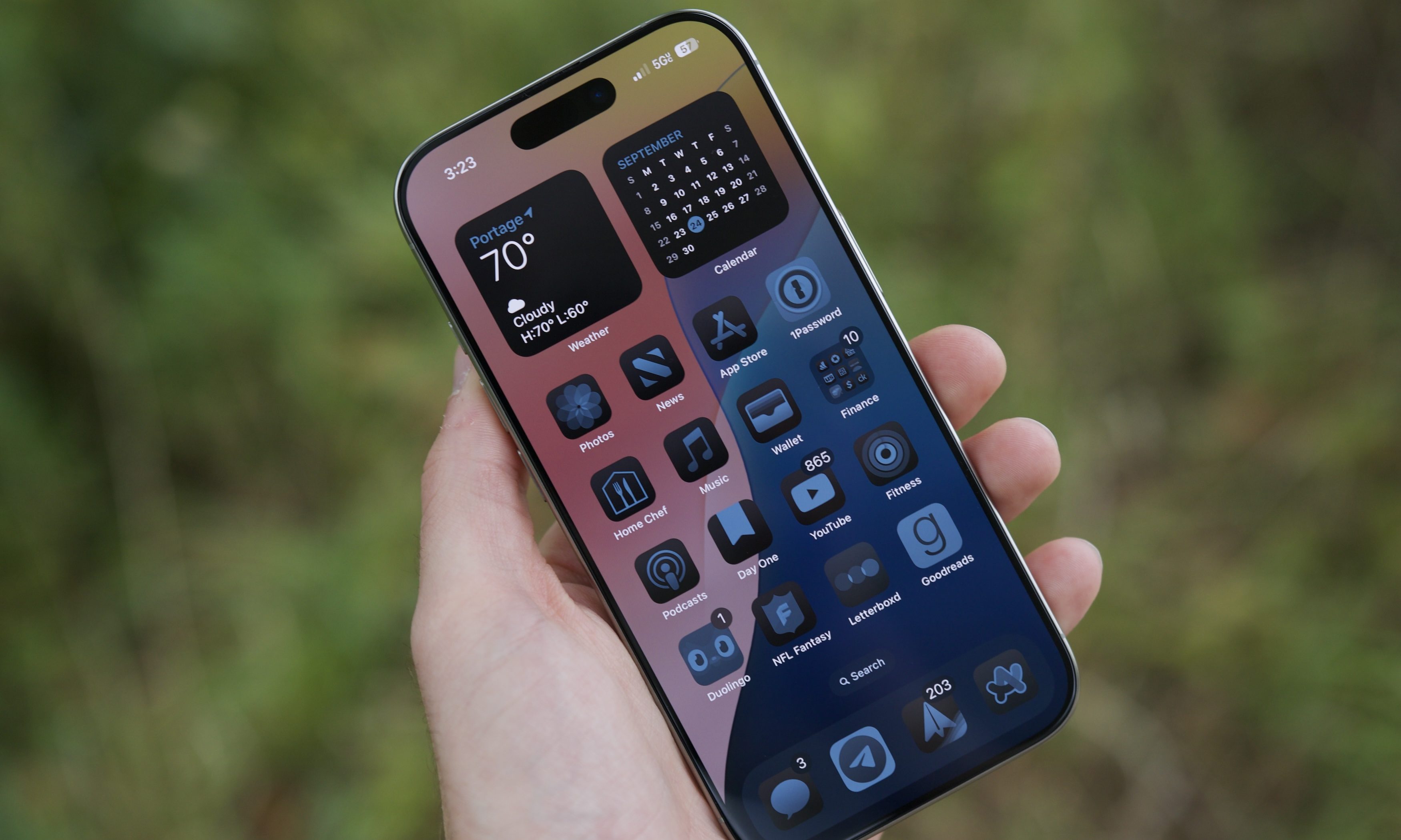 An iPhone 16 Pro displaying its redesigned iOS 19 home screen with updated icons and widgets.