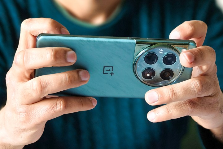 Person holding green OnePlus 12 phone in hands while playing games.