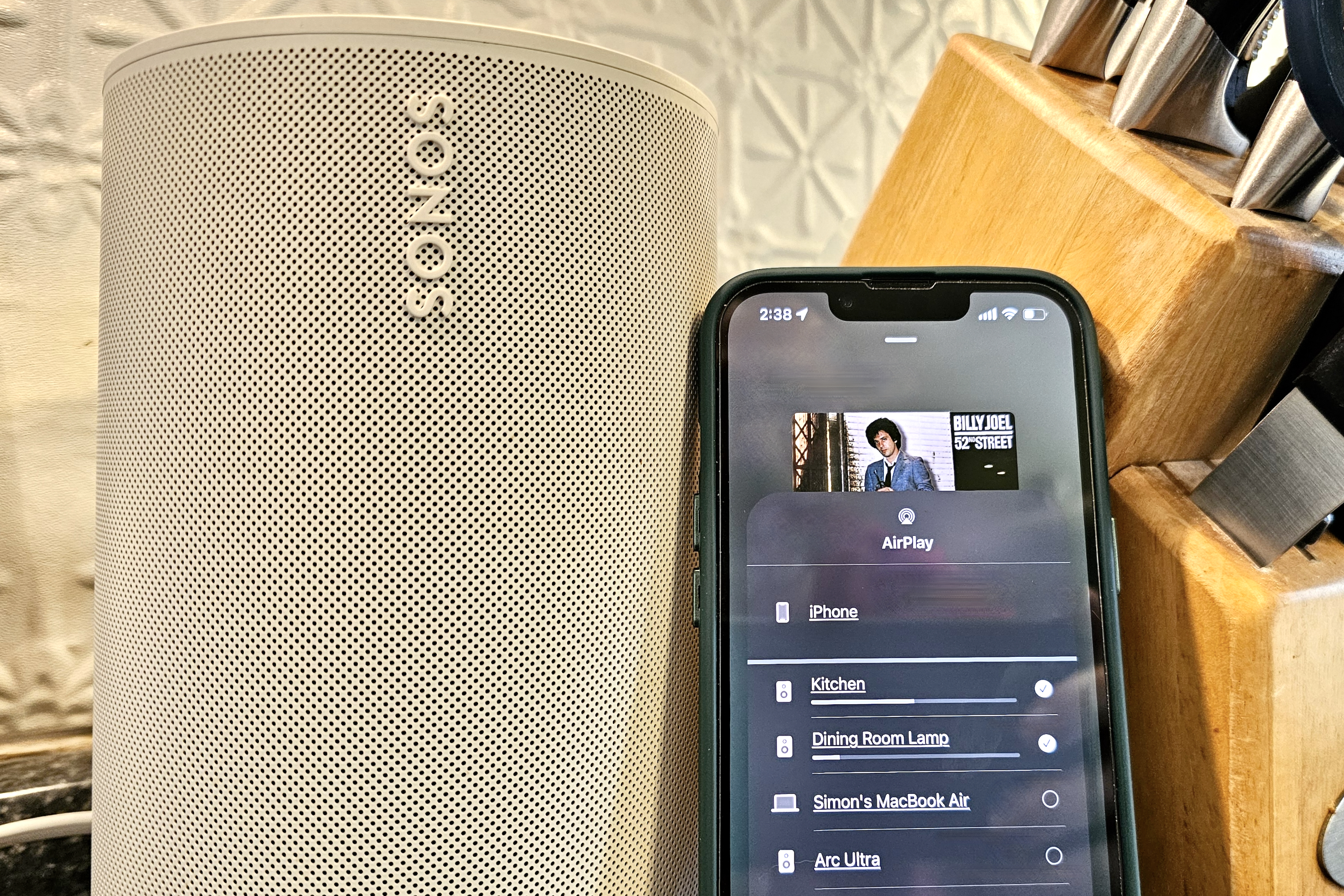 iPhone displaying AirPlay speaker selection menu next to a Sonos Era 100, illustrating broad device compatibility and potential AirPlay security vulnerabilities.