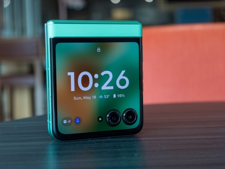 alt: The Motorola Razr 2025 in Spring Bud green, folded and standing upright with the cover display illuminated.