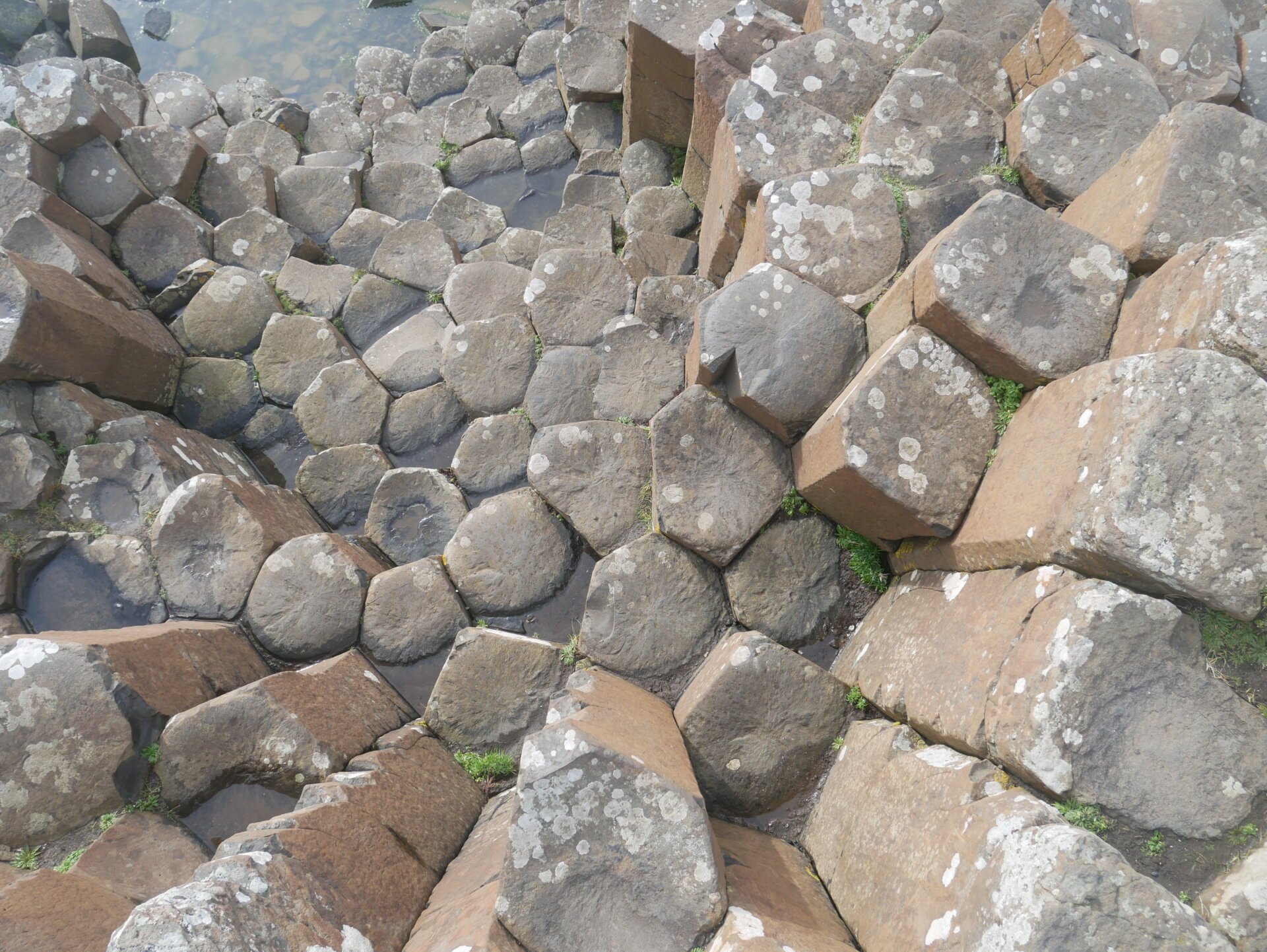 Aerial view of Giant's Causeway basalt columns showing the intricate hexagonal patterns vulnerable to damage from coins.