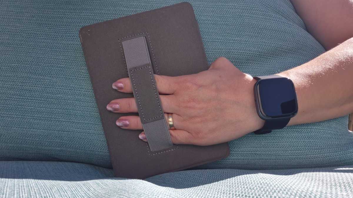 Kindle Paperwhite displayed in a black case featuring a central elastic hand strap for improved grip.