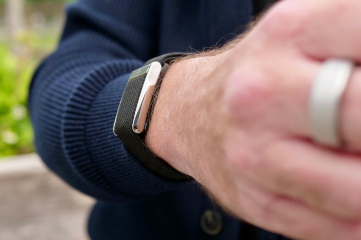Close-up side view of the Whoop 5.0 fitness tracker module on a person's wrist, highlighting its sleek black design.