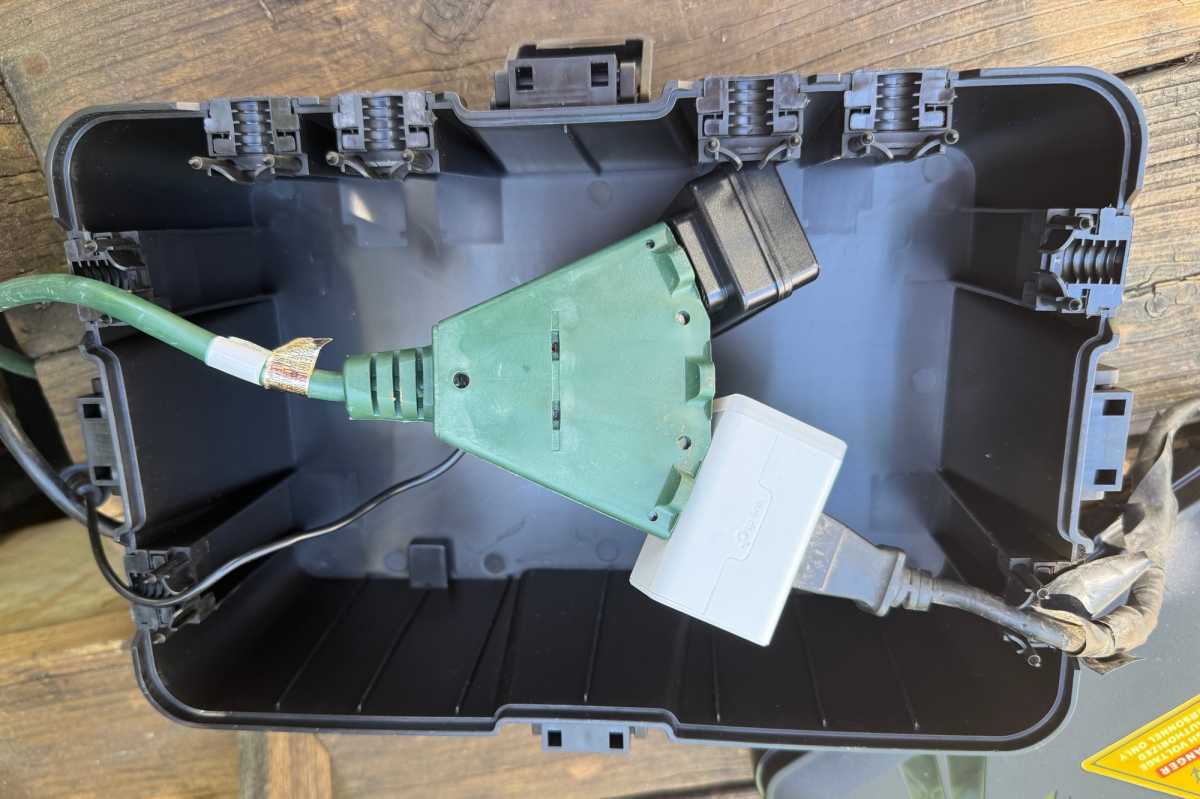 Interior view of the Iwillink outdoor electrical box housing an extension cord with bulky smart plugs connected.