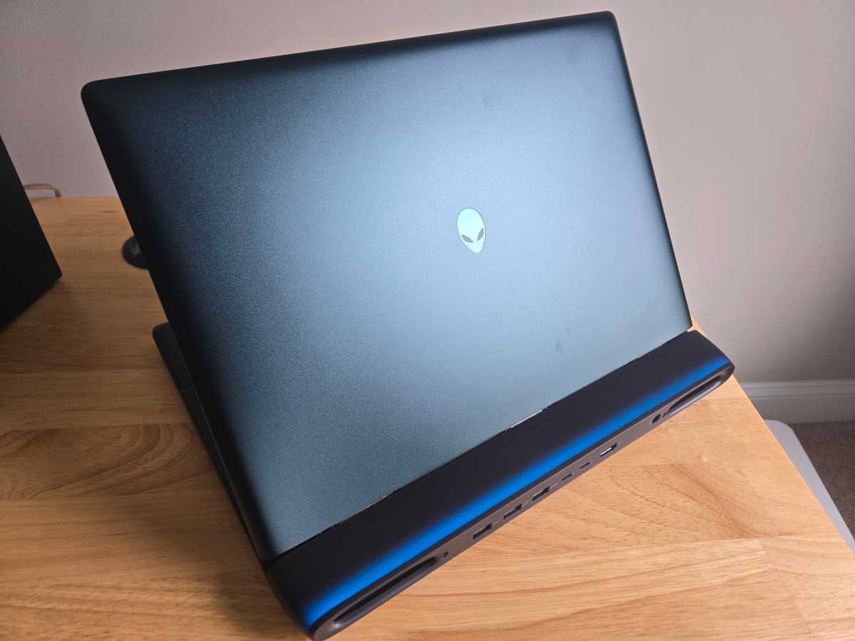 Angled rear view of the Alienware 16 Area-51 gaming laptop in Liquid Teal, showcasing its distinctive design and glowing logo.
