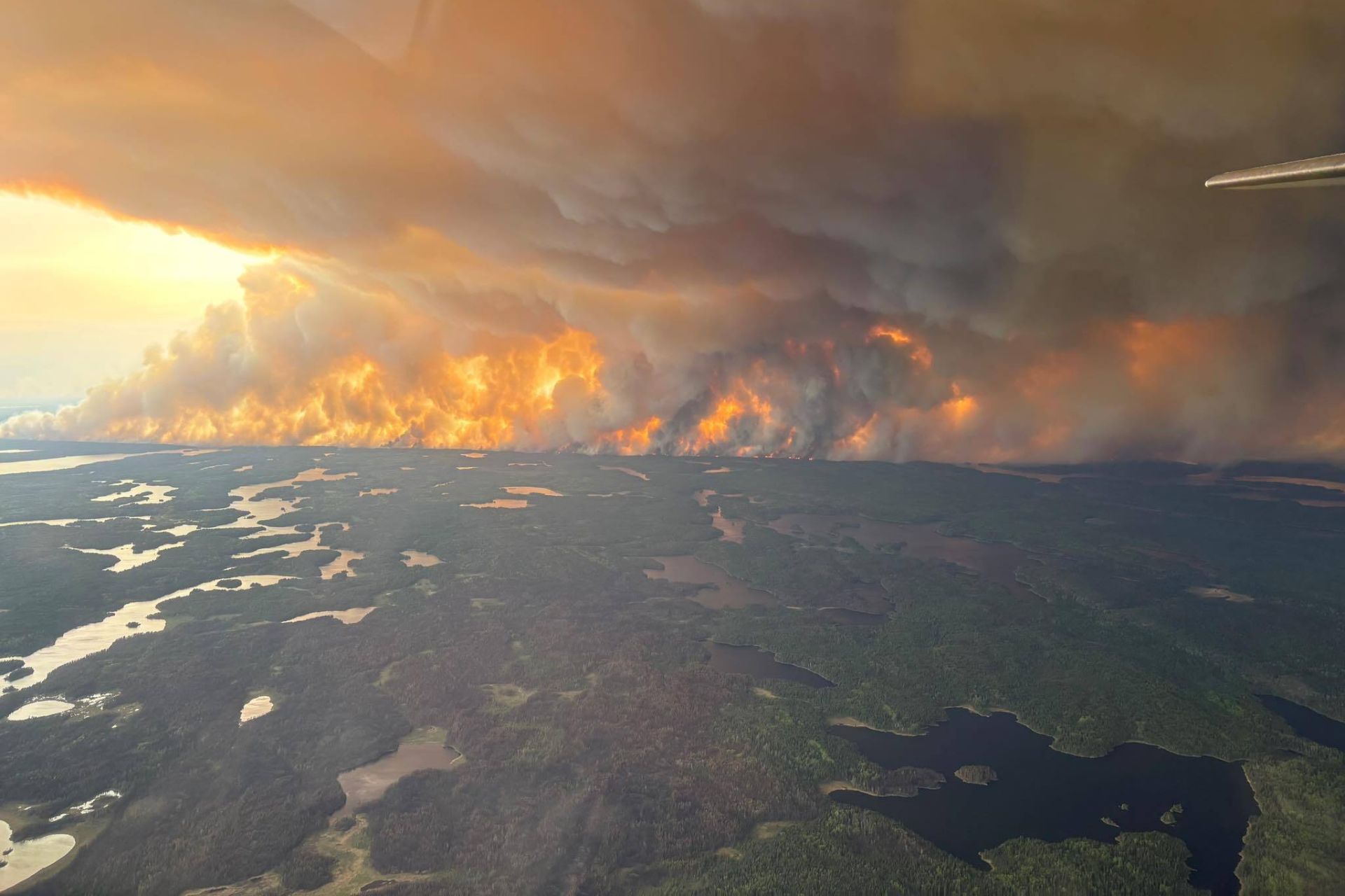 Dense grey smoke billowing from a Canadian wildfire in Flin Flon, Manitoba, illustrating the source of hazardous air pollutants and airborne pathogens.